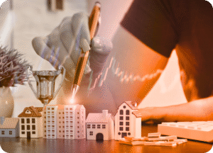 Mão segurando uma caneta sobre pequenos modelos de casas, com notas de dinheiro e um troféu ao lado. Sobreposição de gráficos de crescimento financeiro em tom laranja, simbolizando investimento e sucesso imobiliário.